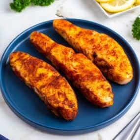 Three air fryer halibut fillets on a blue plate.