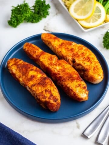 Three air fryer halibut fillets on a blue plate.