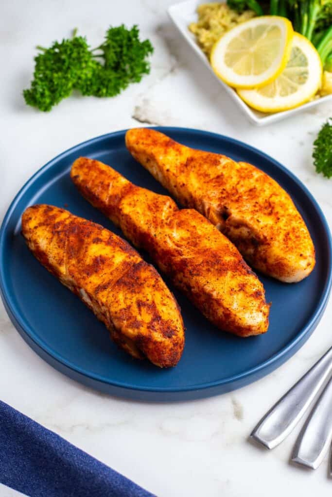 Three air fryer halibut fillets on a blue plate.