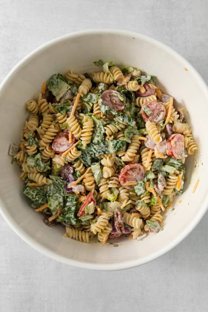 Combining the main ingredients and dressing for a BLT Pasta Salad