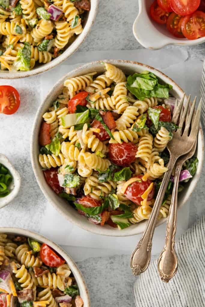 Overhead view of an assembled BLT Pasta Salad with forks resting on top of the bowl.