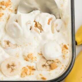 Close up of the banana pudding with condensed milk with a spoon scooping it out of the baking dish.