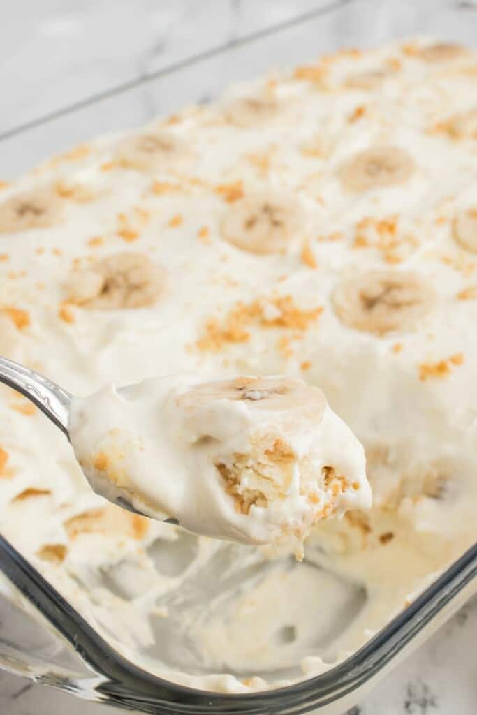 Using a serving spoon to serve a slice of fresh banana cream pudding.