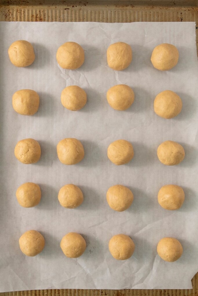 scooping out peanut butter balls onto baking sheet with parchment paper. 