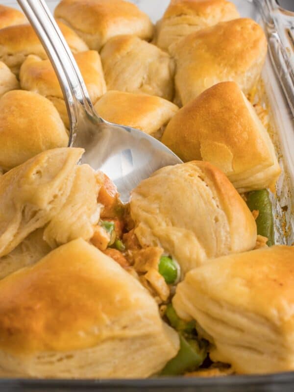 Close up of the chicken pot pie with Grands biscuits with a spoon about to scoop some out of the casserole dish.