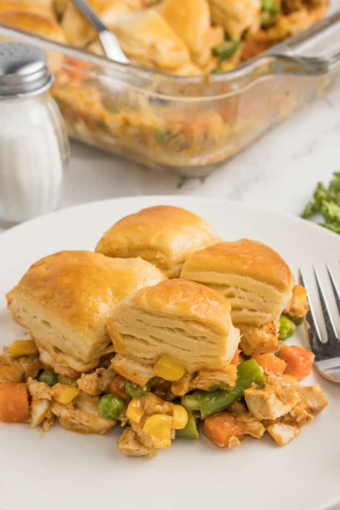 A side view of a single serving of biscuit topped chicken pot pie on a plate.