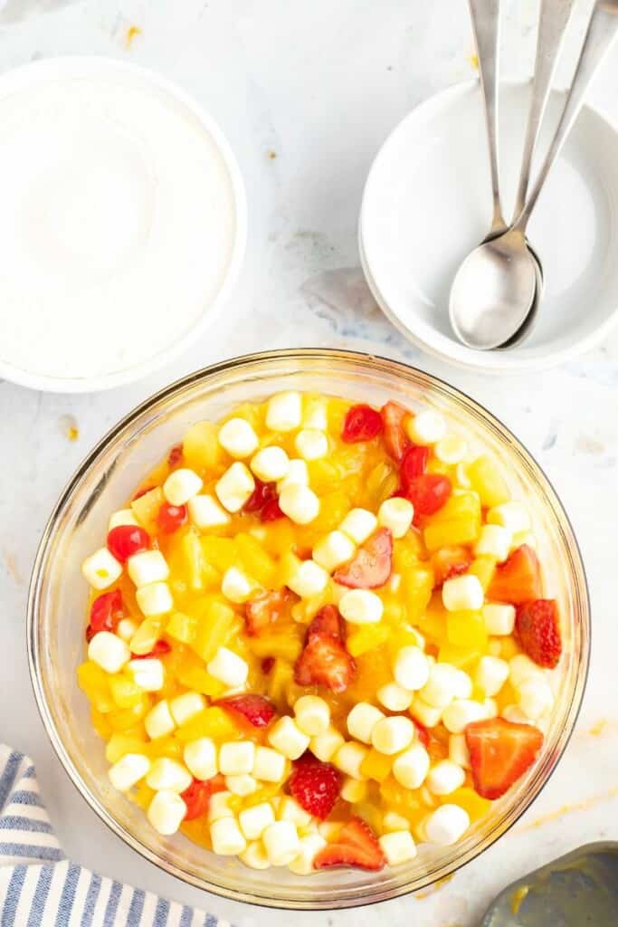Mixing in mini marshmallows with fruit fluff salad. 