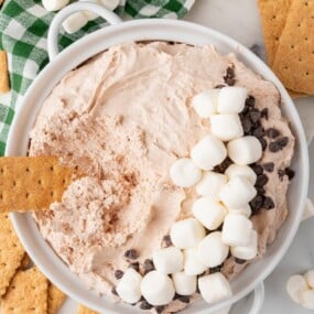A bowl of hot cocoa dip topped with mini marshmallows and chocolate chips.