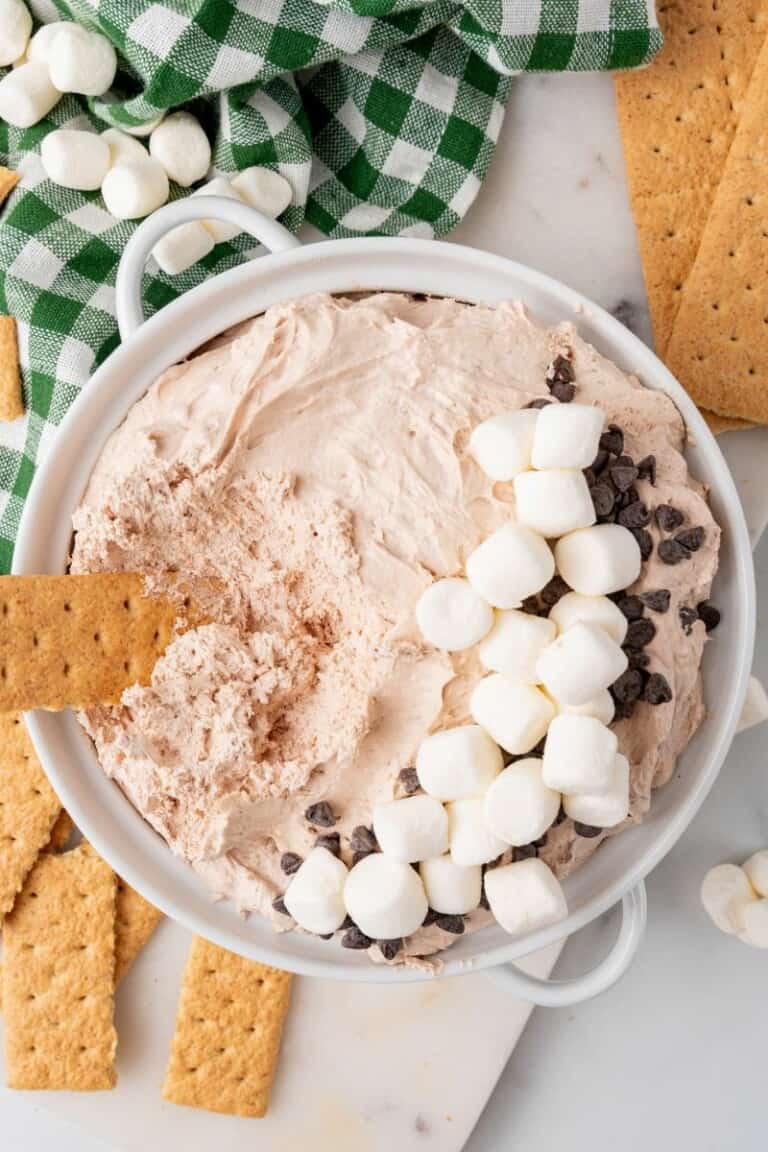 A bowl of hot cocoa dip topped with mini marshmallows and chocolate chips.