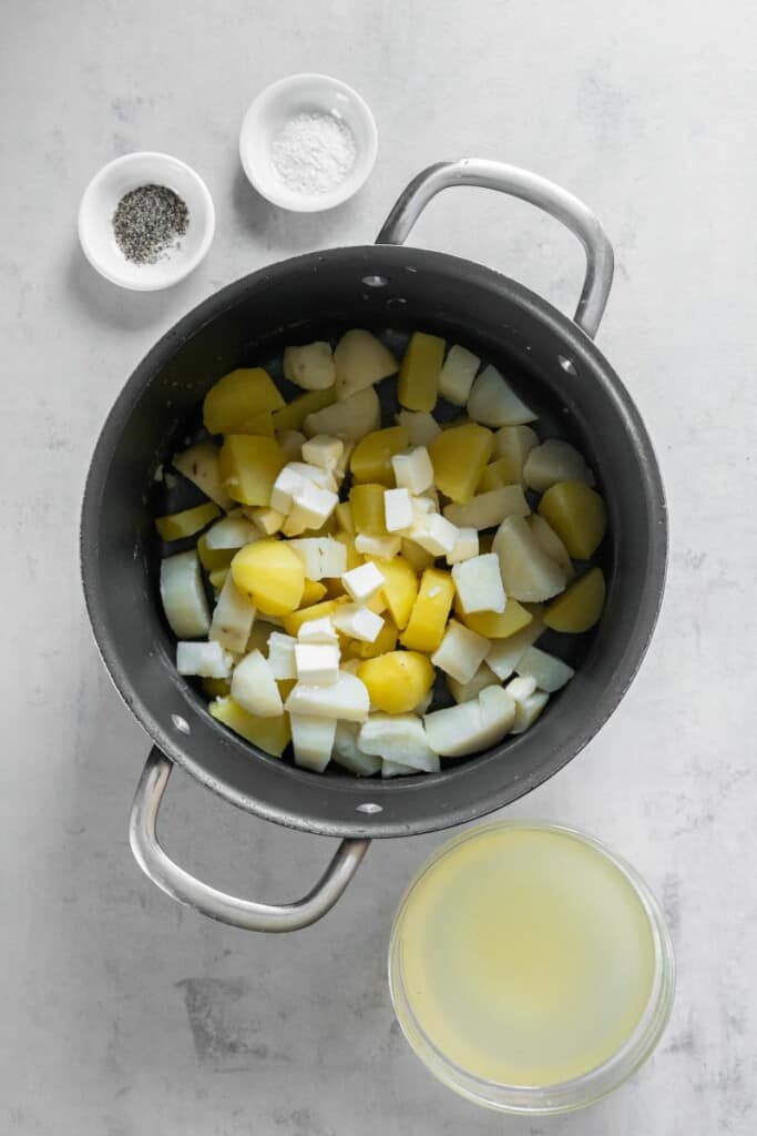 adding cubed butter to cook potatoes in a pot. 