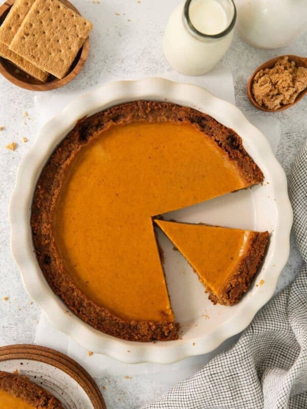 Sweet potato pie in a graham cracker crust with one slice taken out and another slice in the pie pan.