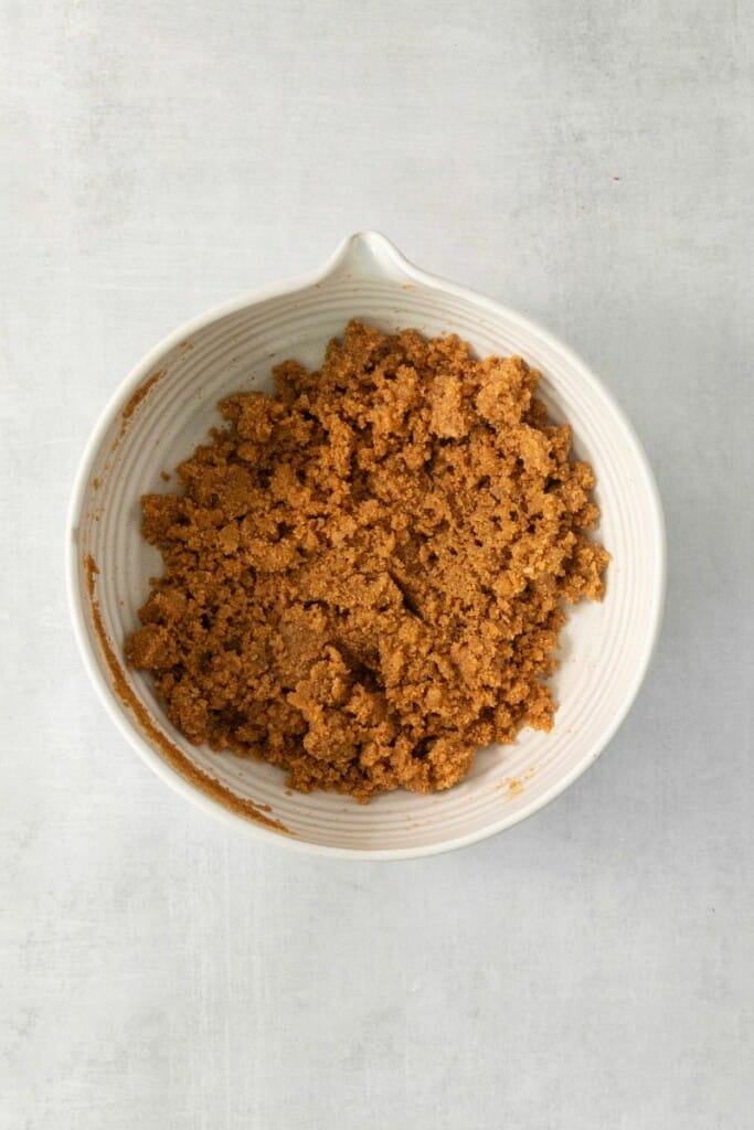 Combining the ingredients for a graham cracker pie crust in a mixing bowl.