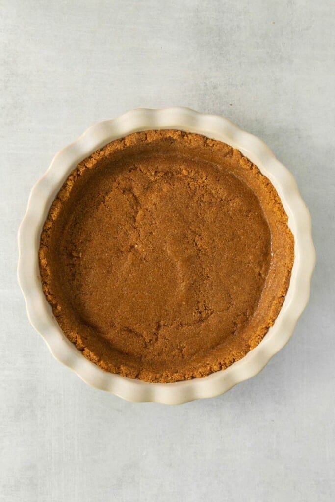 A graham cracker pie crust in a pie dish.