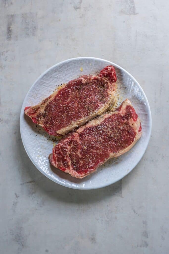 New York strip steak seasoned on a plate.