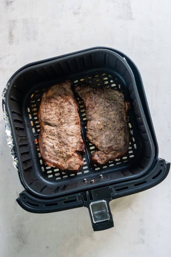 Cooked NY strip in an air fryer basket.