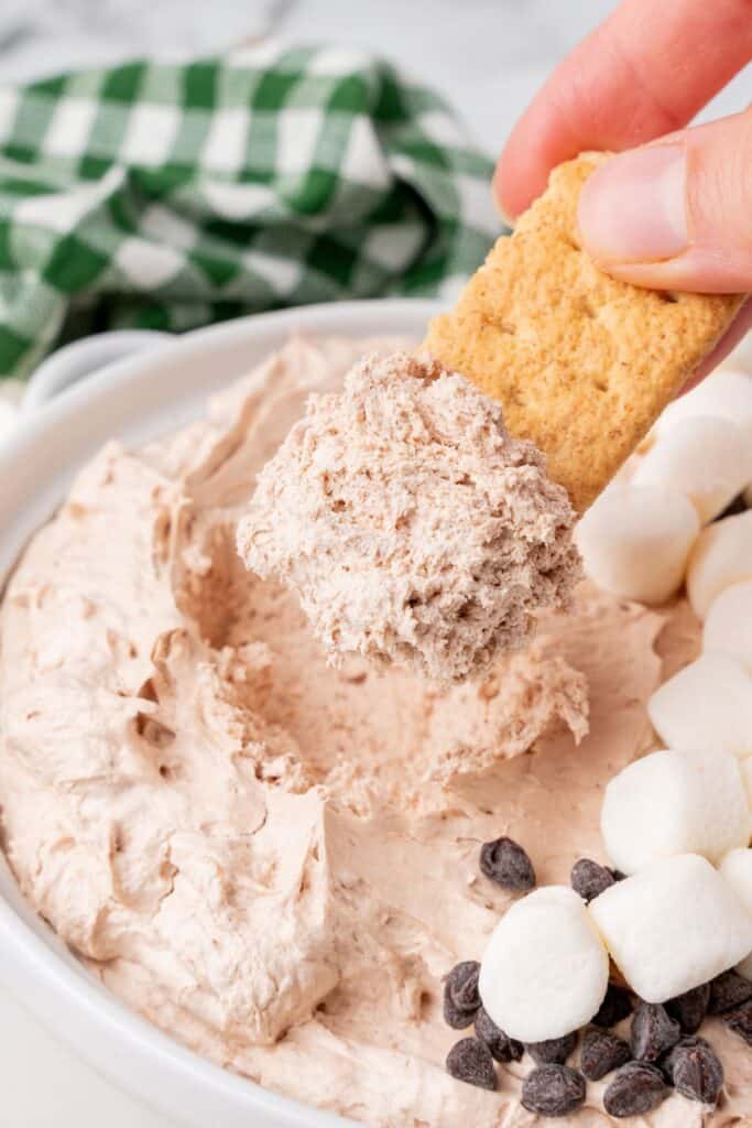 A close up of a graham cracker being dipped into the hot chocolate dip.