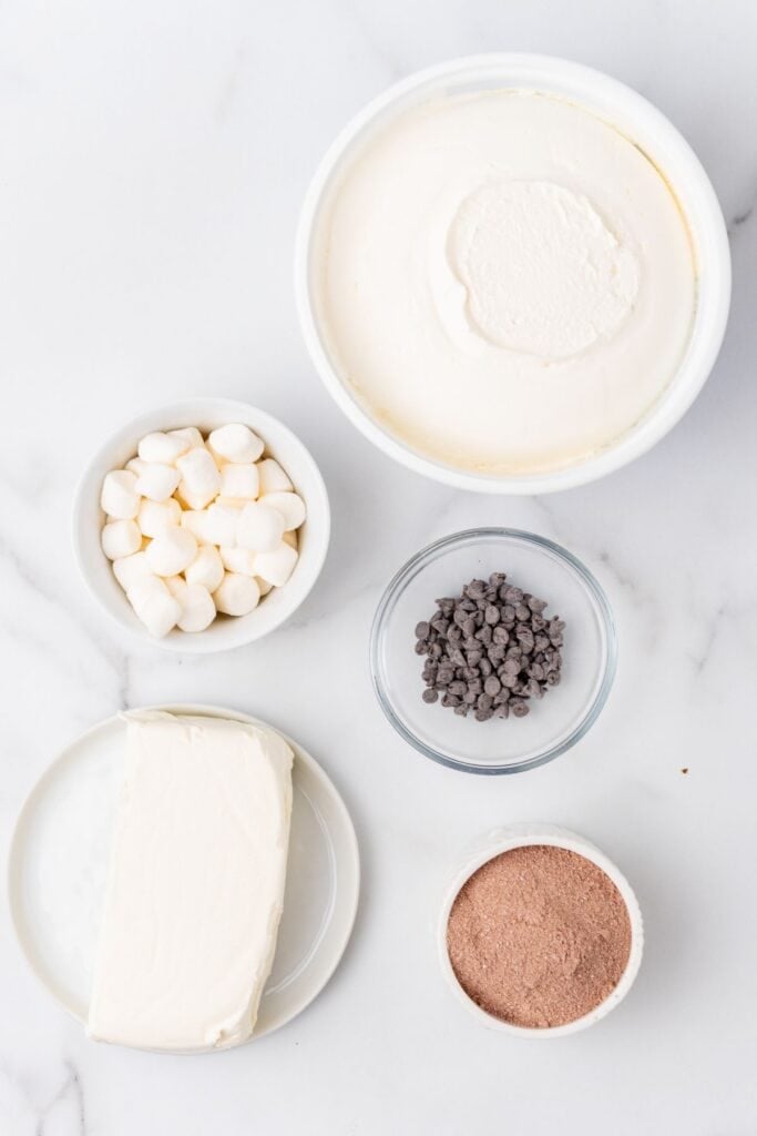 Ingredients to make hot cocoa dip: cream cheese, hot cocoa mix, Cool Whip, marshmallows, and mini chocolate chips.
