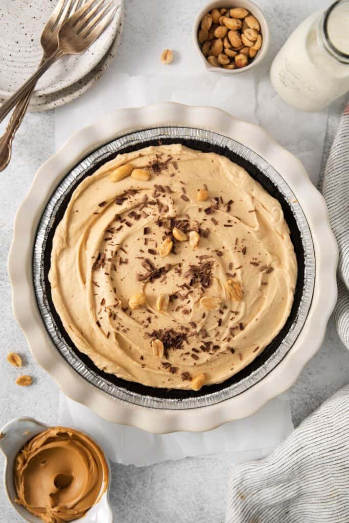 Peanut butter pie with cool whip in an Oreo crust topped with peanuts and chocolate shavings.