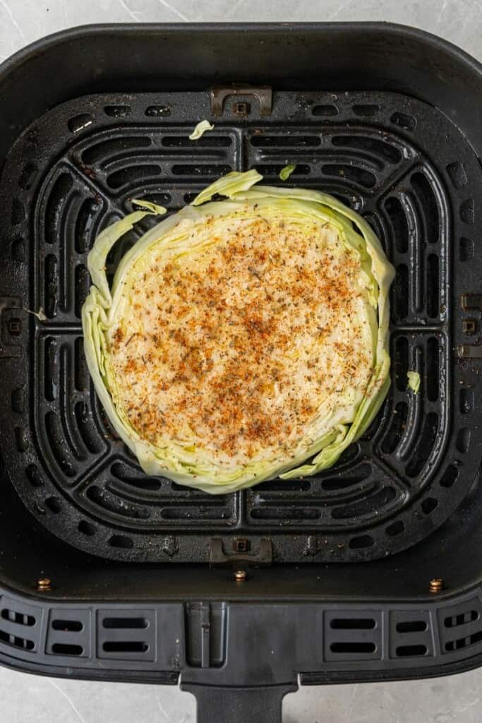 adding a slice of cabbage into the air fryer with spices 