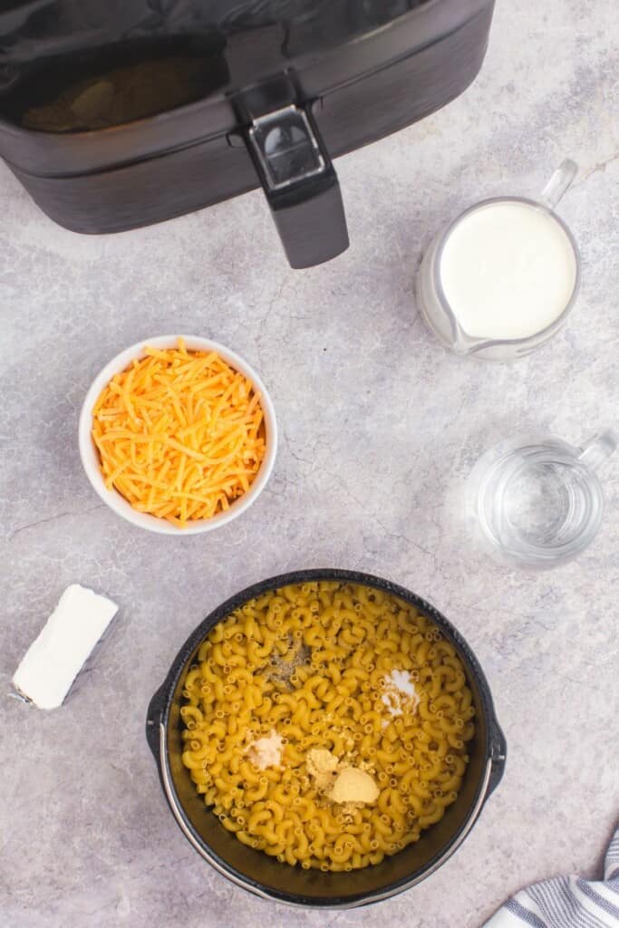 adding dry noodles and seasoning to air fryer pot. 