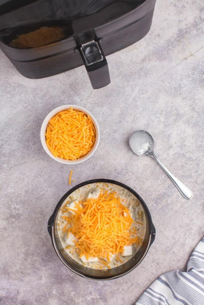 adding in shredded cheddar cheese on top of dry noodles 