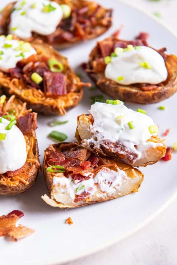 taking a bite out of loaded potato skins on a plate. 