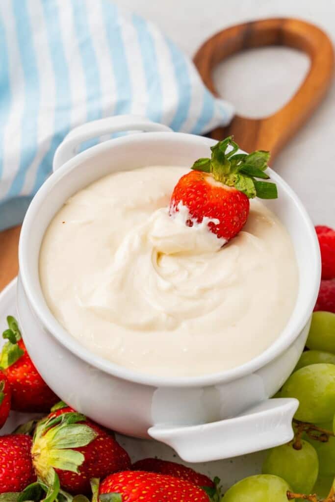 dipping a strawberry into cream cheese fruit dip recipe. 