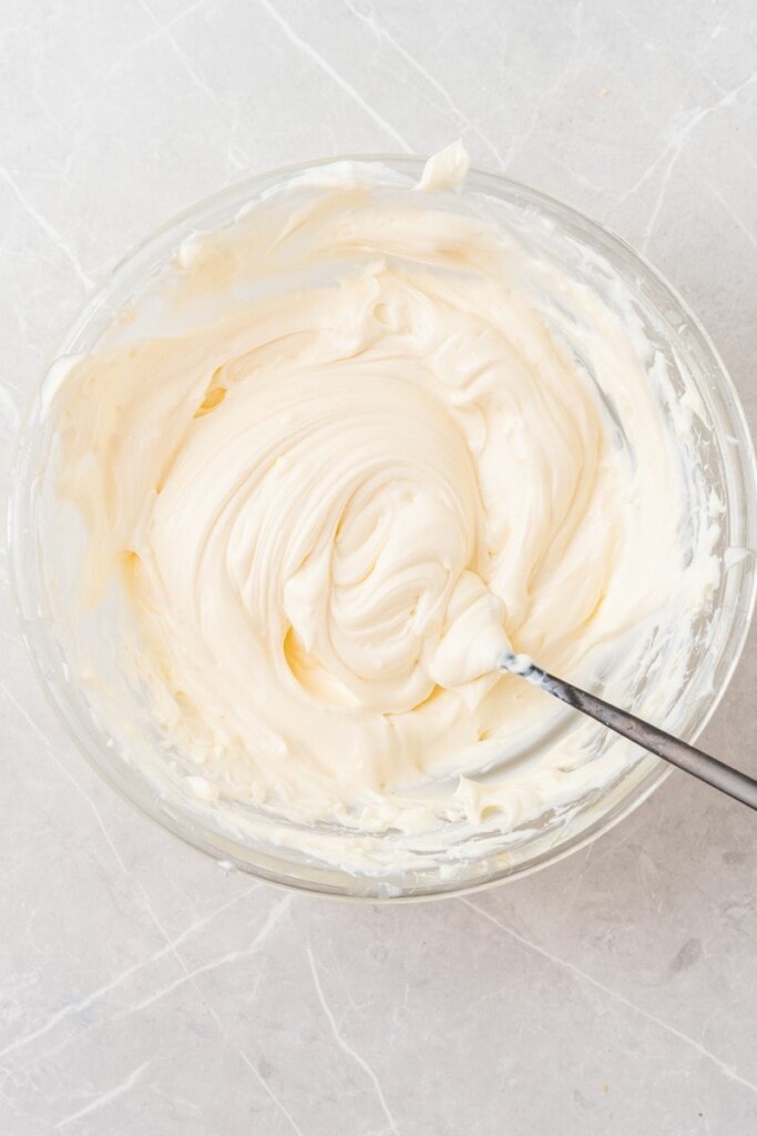 Mixing cream cheese and greek yogurt in glass bowl. 