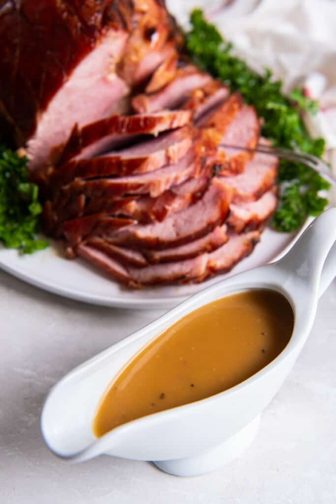 ham gravy in a gravy bowl with a whole ham. 