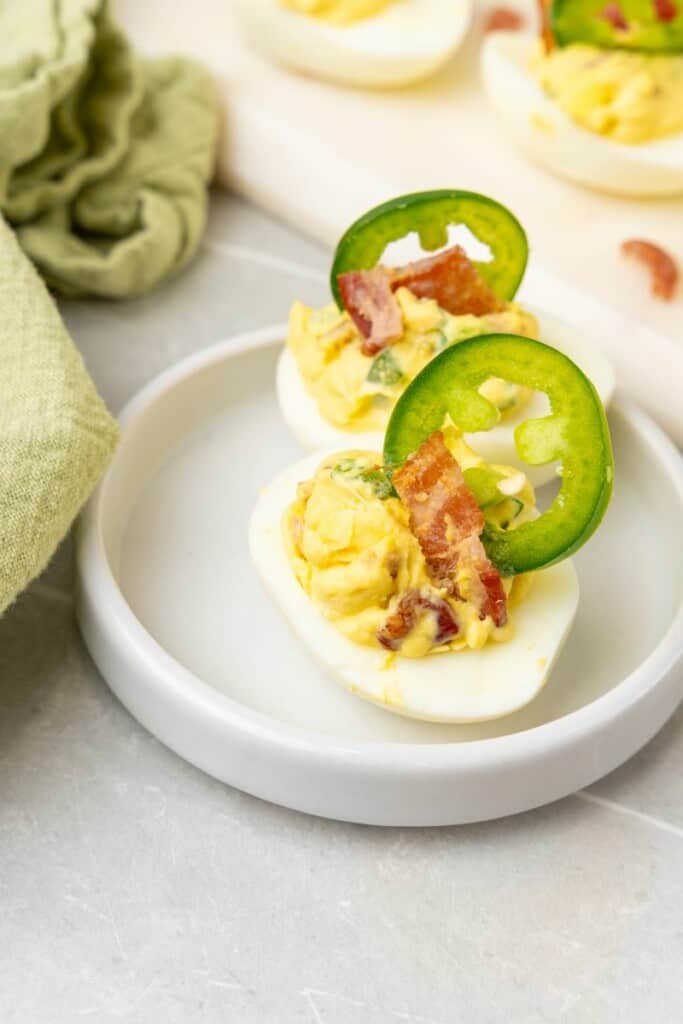 serving two jalapeno deviled eggs on a white plate. 