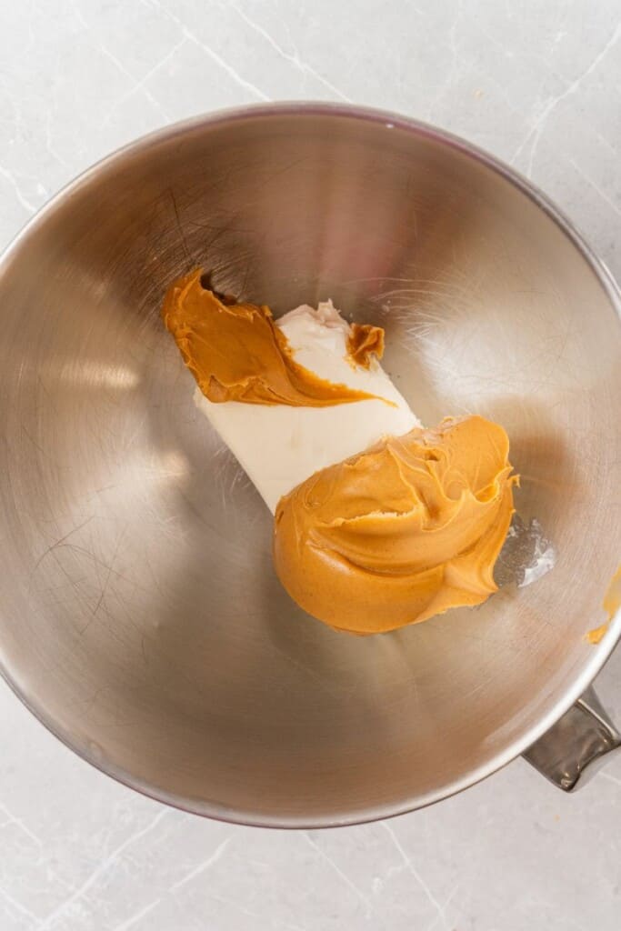 adding creamy peanut butter and cream cheese to a bowl. 