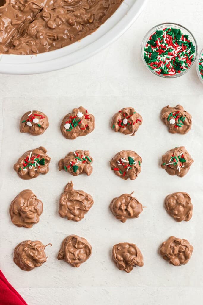 adding christmas sprinkles over chocolate peanut bites. 