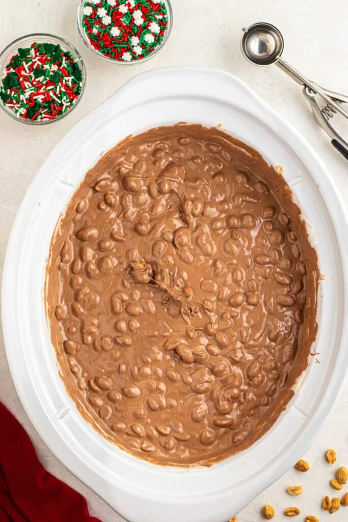 stirring chocolate with peanuts in slow cooker
