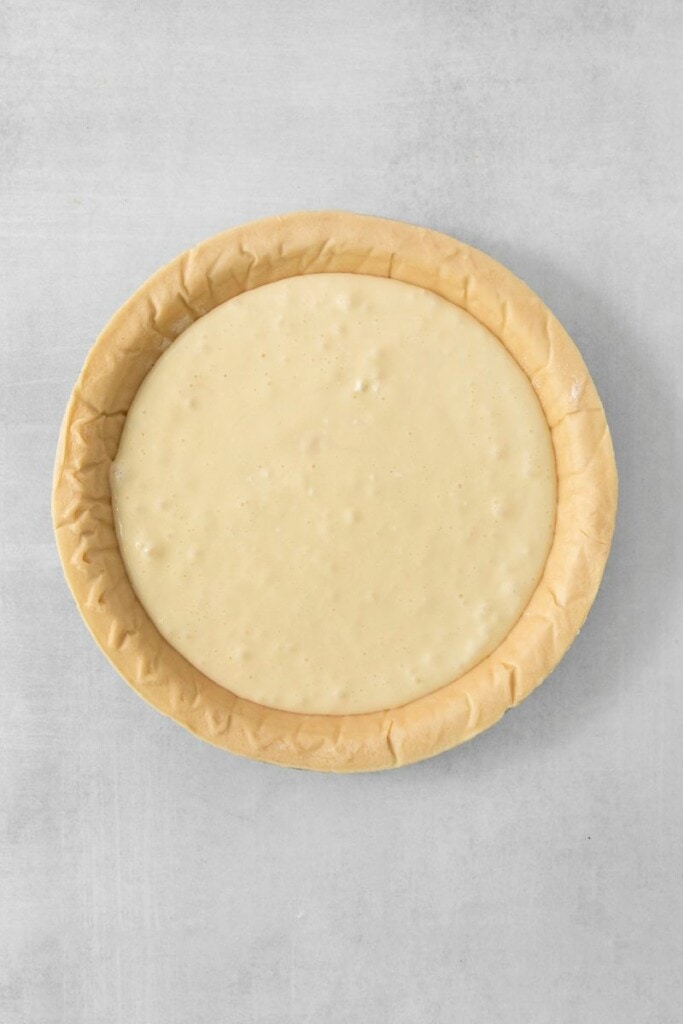 adding cream cheese layer to the prepared pie crust.