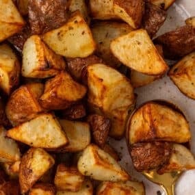 air fryer red potatoes cooked on a white plate with a spoon.