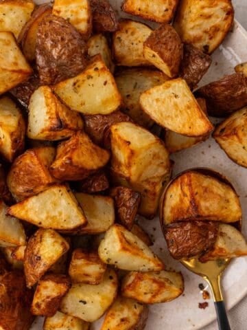 air fryer red potatoes cooked on a white plate with a spoon.