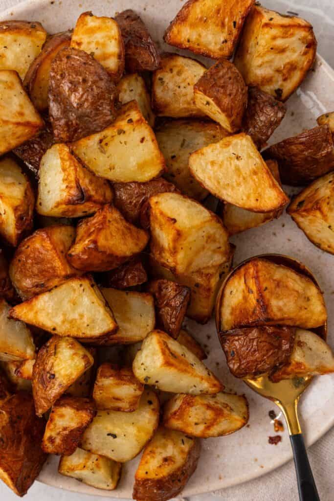 air fryer red potatoes cooked on a white plate with a spoon.