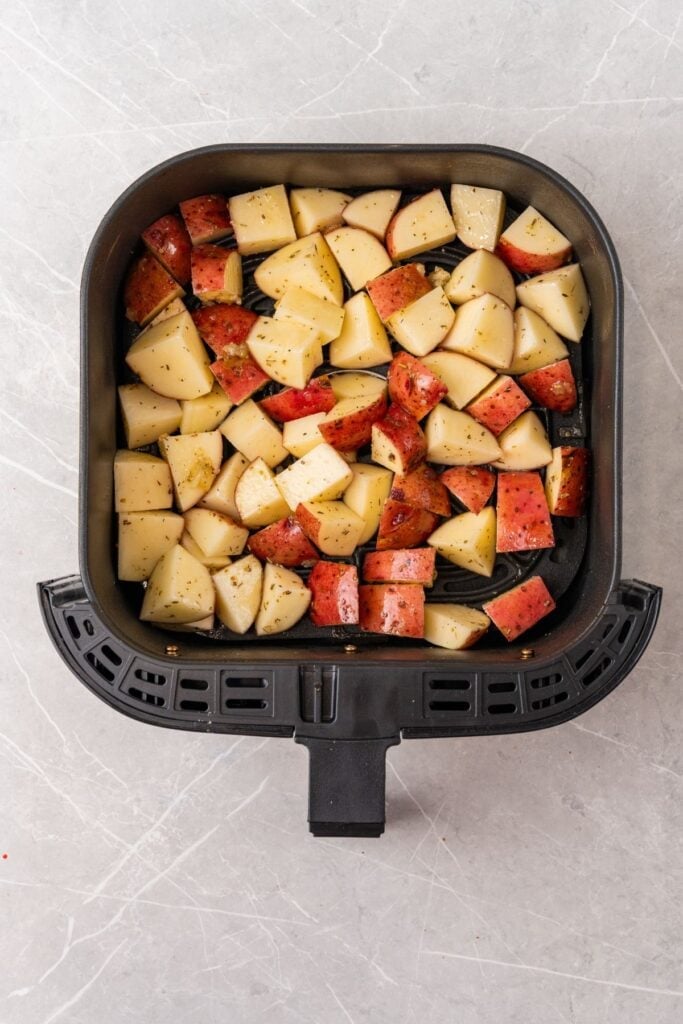 Raw red potatoes in an air fryer basket.