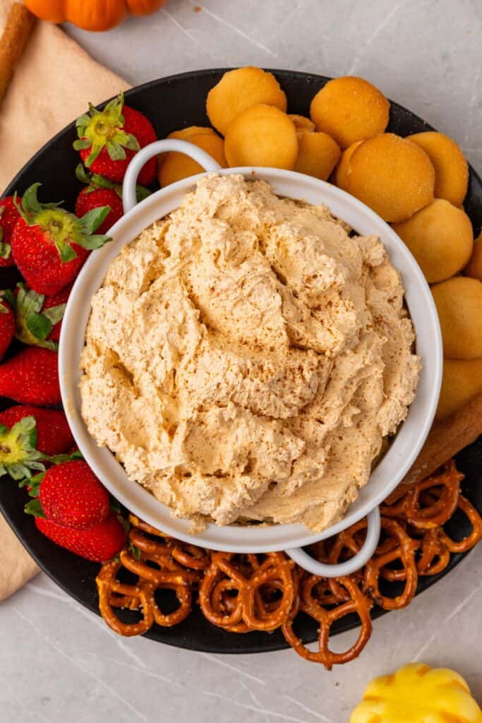 Overhead view of pumpkin dip with strawberries, pretzels, and Nilla wafers surrounding the bowl.