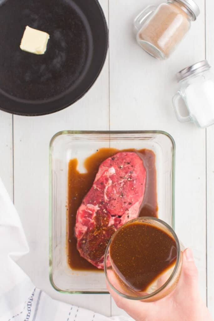 pouring soy sauce marinade over piece of steak