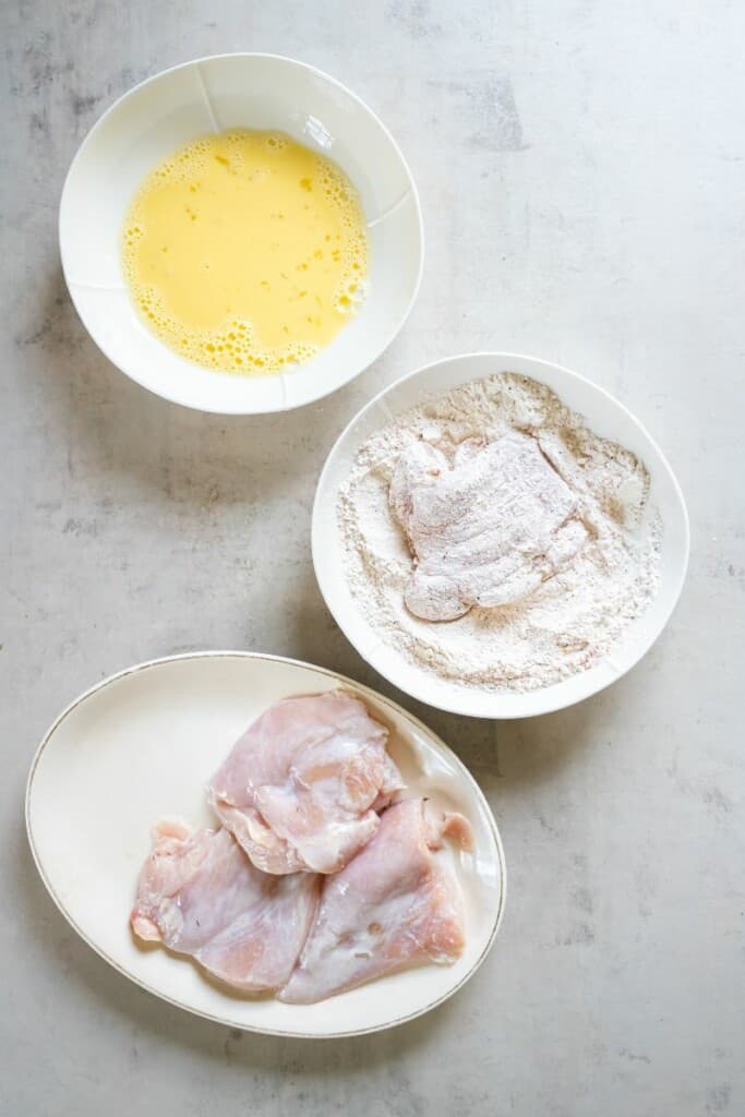 dredging marinated chicken through flour