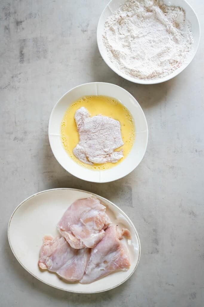 dipping marinated chicken into egg wash 