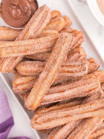 air fryer churros stacked on top of each other with dipping sauce