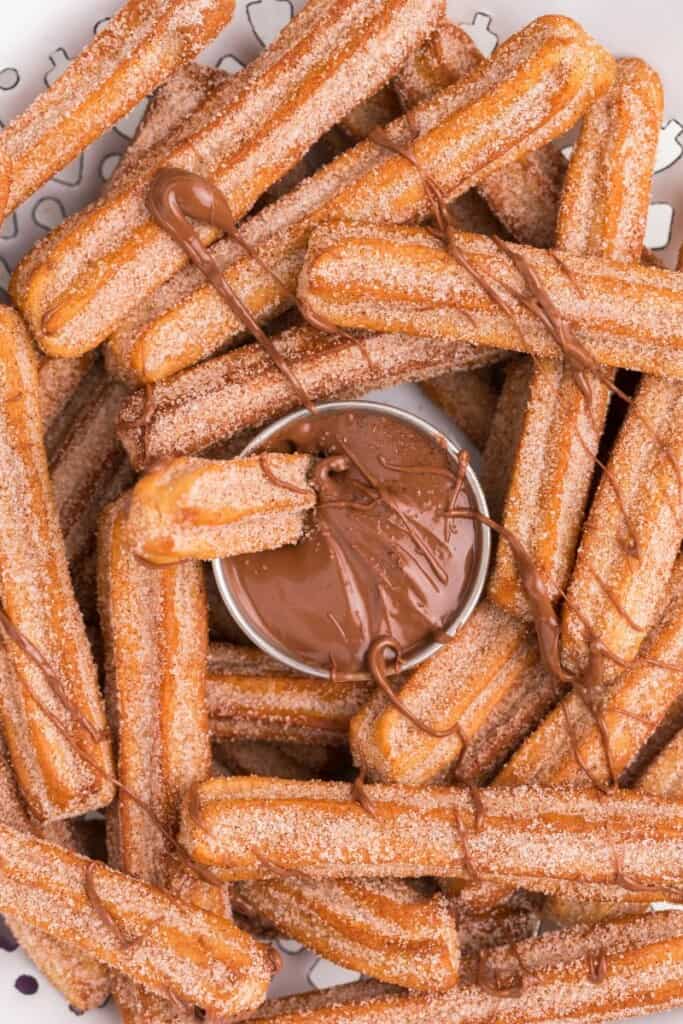 drizzling melted nutella over air fryer churros on a plate