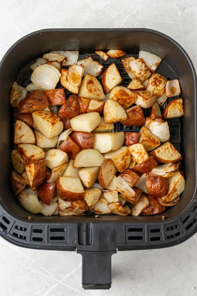 air fryer potatoes and onions in the air fryer basket cooked