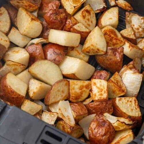 roasted potatoes and onions in an air fryer basket