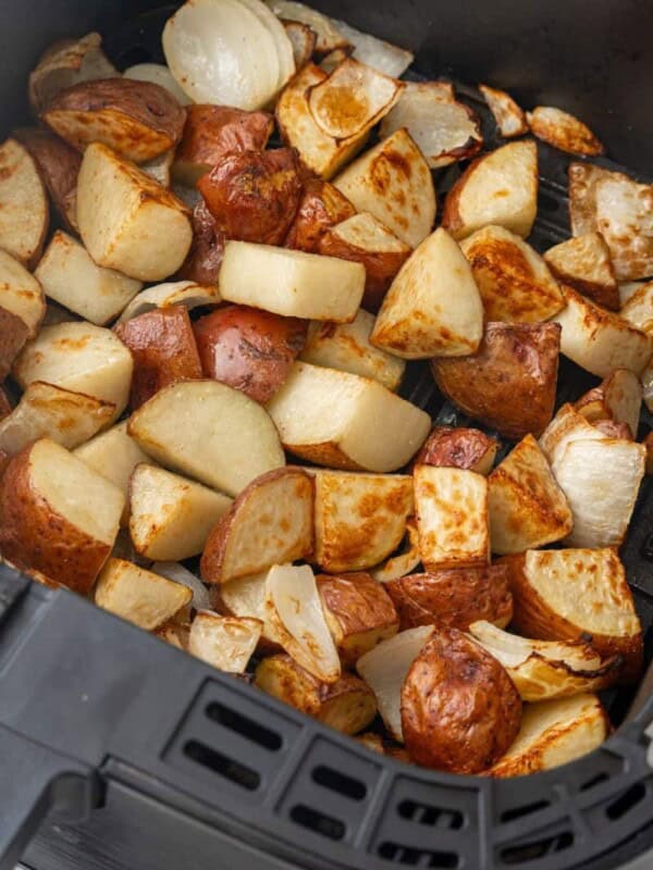 roasted potatoes and onions in an air fryer basket