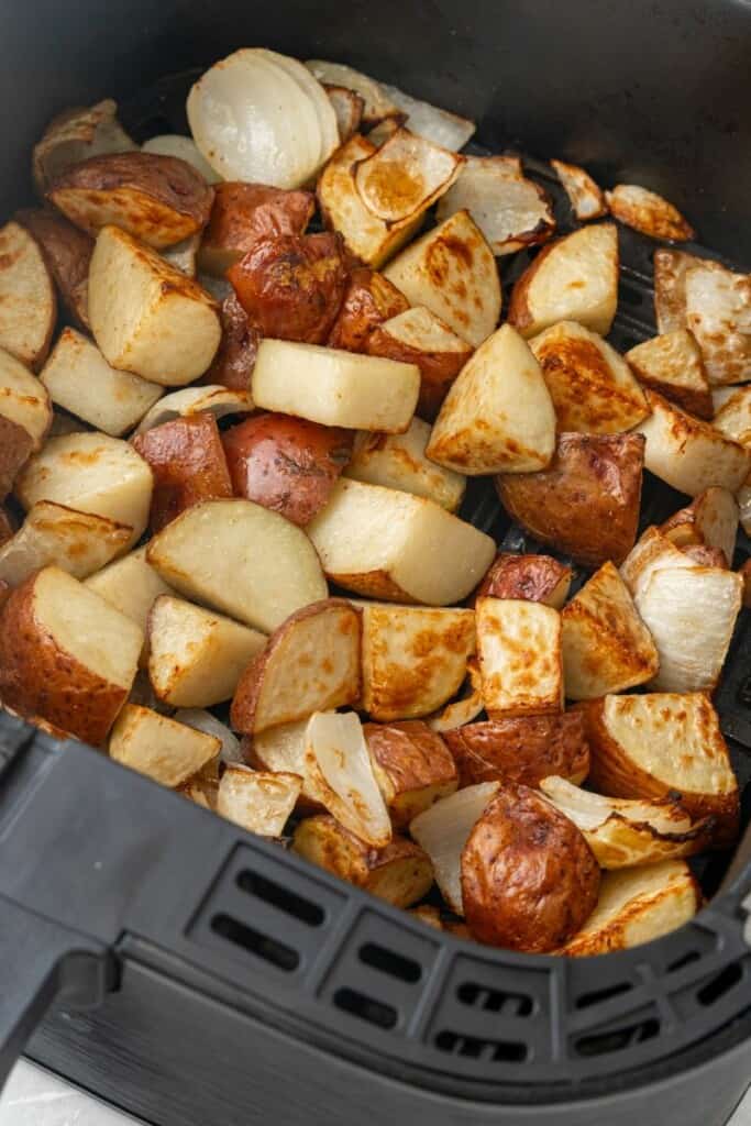 roasted potatoes and onions in an air fryer basket