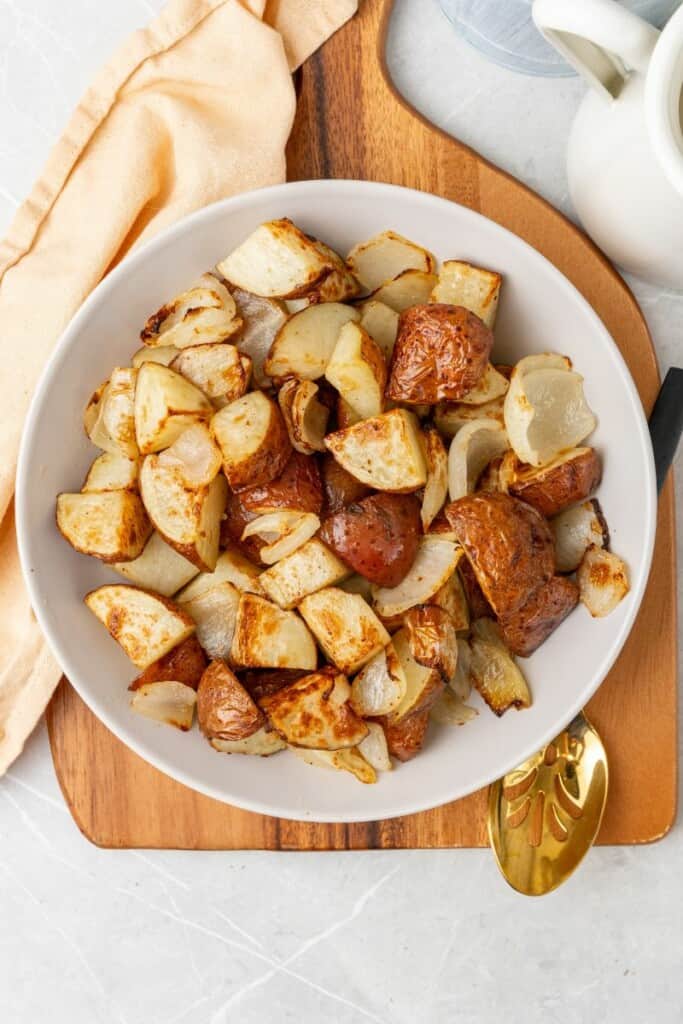 overhead shot of air fried potatoes and onions in a white bowl 