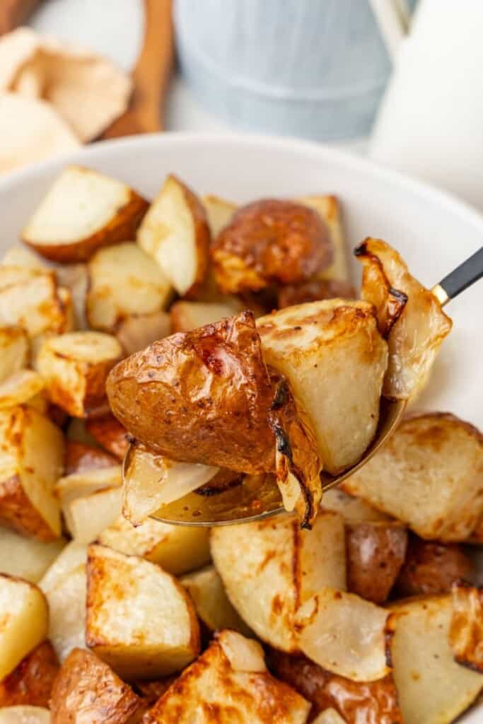 using a spoon to scoop up air fried potato and onions 